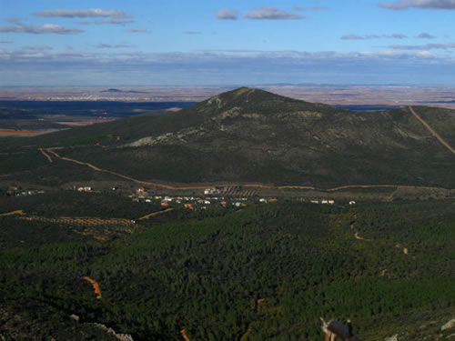 Desde los aledaños de la cumbre, el camino gira y desciende bruscamente hacia el nordeste, paralelo a la valla. Unos metros más abajo, se ciñe a unos llamativos escarpes y los sortea por la derecha. Continúa después más o menos paralelo al que utilizamos para subir, sólo que a más altura, lo que nos permite ir disfrutando de unas hermosas vistas sobre el valle, la colonia de Cinco Casas y la Loma de los Carros.